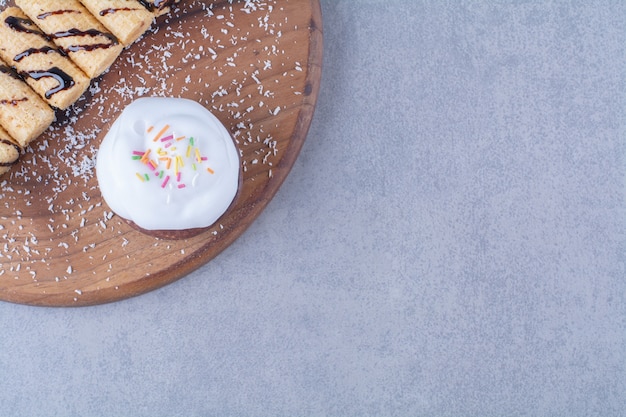 Foto gratuita una tabla de madera de palos dulces con cupcake cremoso con chispitas de colores.