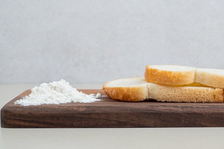 Foto gratuito una tabla de madera de pan blanco fresco en rodajas con harina