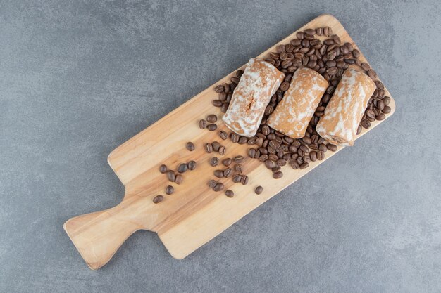 Una tabla de madera con pan de jengibre dulce y granos de café.