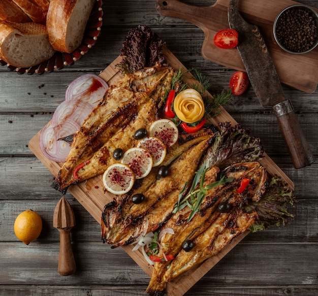 Una tabla de madera con parrillas de pescado y hierbas.