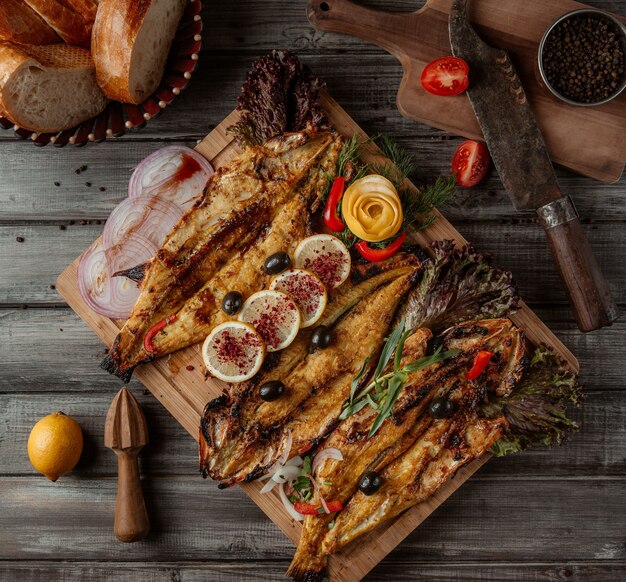 Una tabla de madera con parrillas de pescado y hierbas.