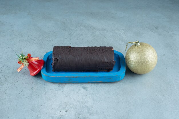 Una tabla de madera con rollo de pastel de chocolate con juguetes navideños.