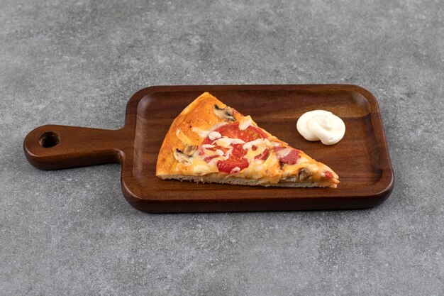 Tabla de madera de sabrosa pizza en rodajas sobre la mesa de piedra.