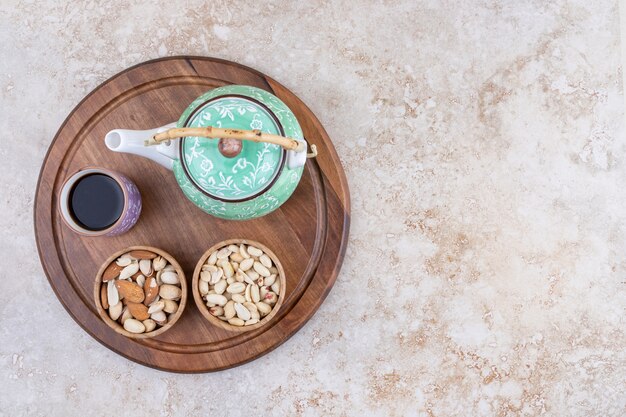 Una tabla de madera con tetera y nueces.