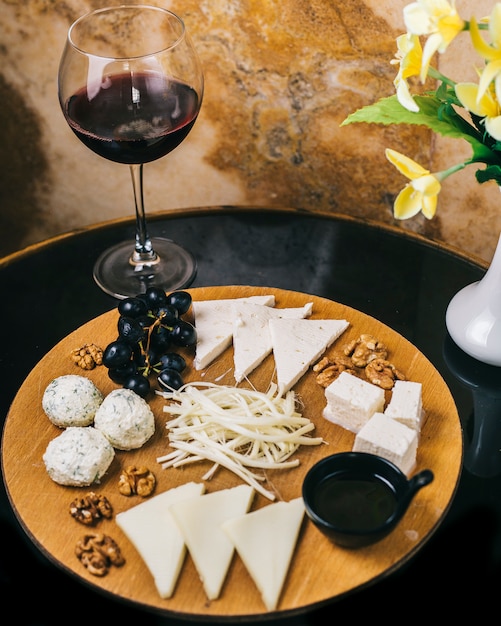 Foto gratuita tabla de quesos con una copa de vino tinto.