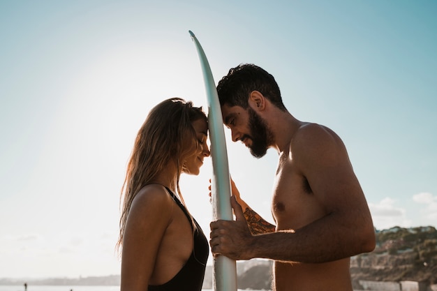 Tabla de surf entre joven sonriente y hombre