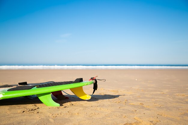 Tabla de surf recortada o longboard tumbado en la playa de arena