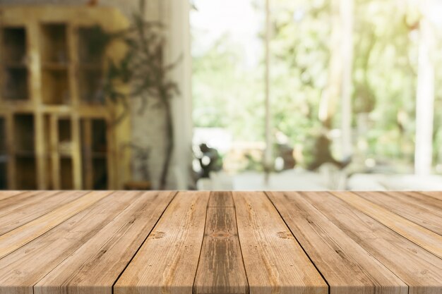 Tabla vacía del tablero de madera delante del fondo borroso. Madera marrón de la perspectiva sobre la falta de definición en cafetería - puede ser utilizado para la exhibición o el montaje de sus productos. Esté preparado para la exhibición del producto.