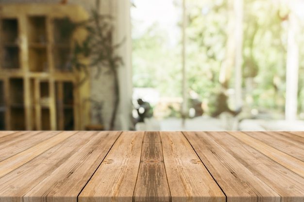 Tabla vacía del tablero de madera delante del fondo borroso. Madera marrón de la perspectiva sobre la falta de definición en cafetería - puede ser utilizado para la exhibición o el montaje de sus productos. Esté preparado para la exhibición del producto.