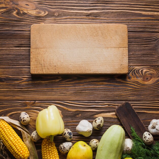 Tabla y verduras en superficie de madera