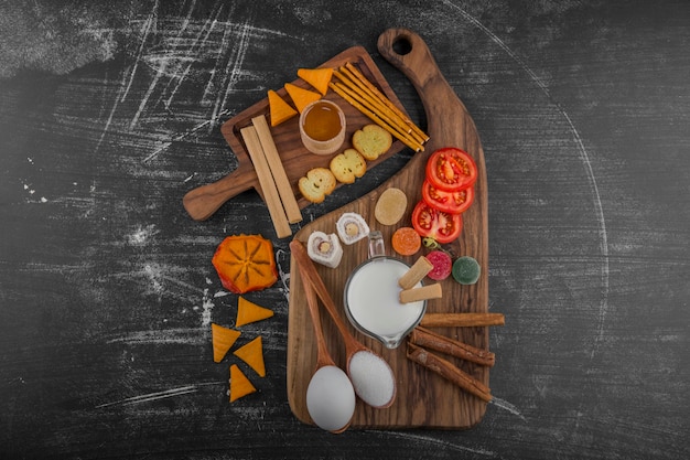 Tablero de aperitivos con galletas y verduras aislado en negro