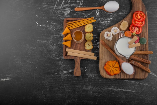 Tablero de aperitivos con galletas y verduras aislado sobre fondo negro