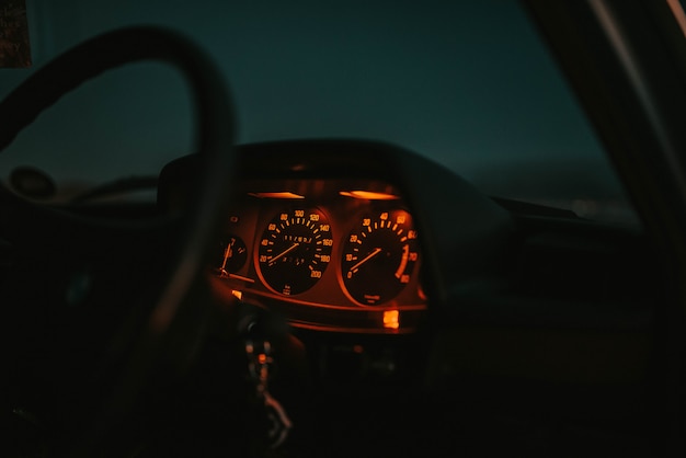 Tablero del automóvil iluminado en rojo con un volante por la noche