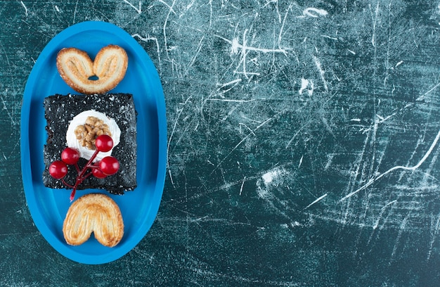 Un tablero azul con un trozo de pastel de chocolate y galletas. Foto de alta calidad