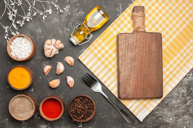 Foto gratuita tablero de especias de vista superior en el mantel a cuadros botella de ajo de tenedor de especias de aceite