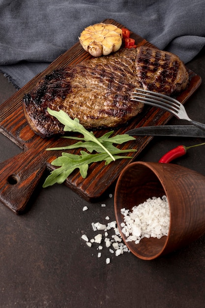 Tablero de madera con carne a la parrilla en el escritorio