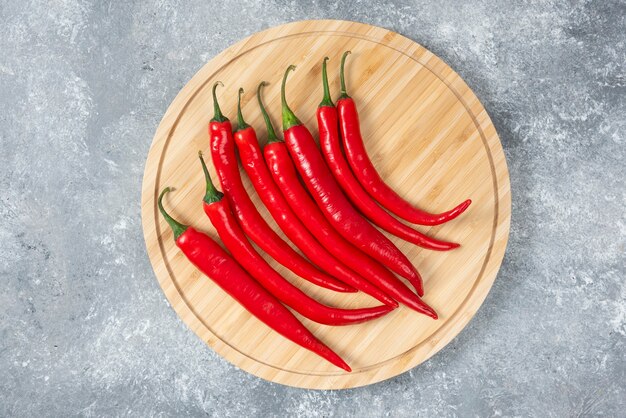 Tablero de madera de chiles rojos sobre superficie de mármol.