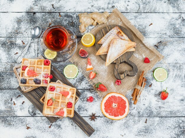 Tablero de madera de gofres y té con frutos rojos y cítricos