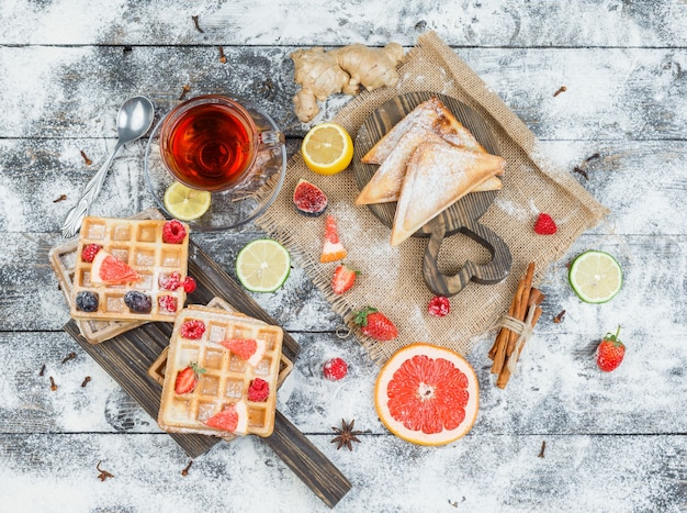 Tablero de madera de gofres y té con frutos rojos y cítricos