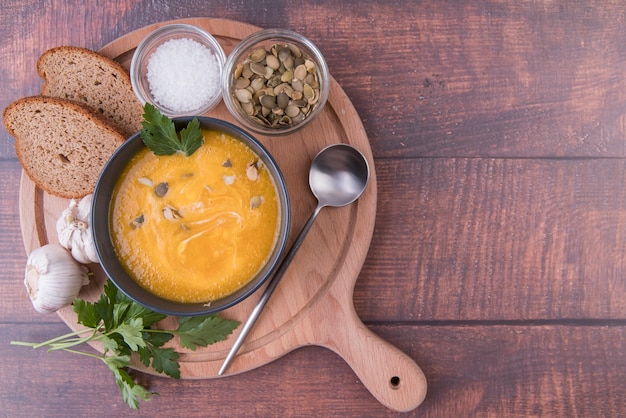 Tablero de madera lleno de tazón de sopa e ingredientes