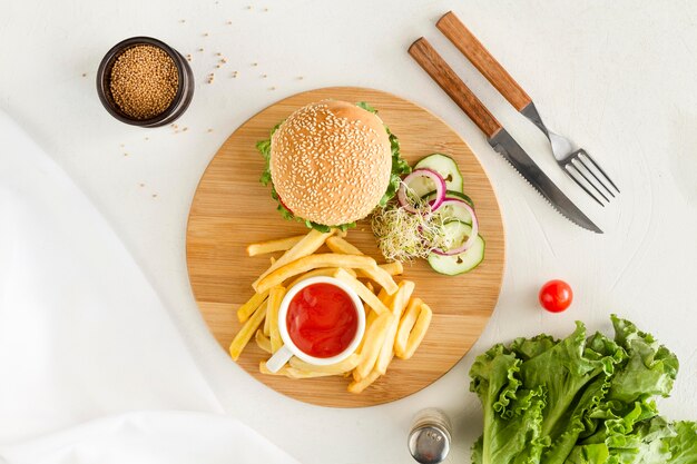 Tablero de madera plano con hamburguesas y papas fritas