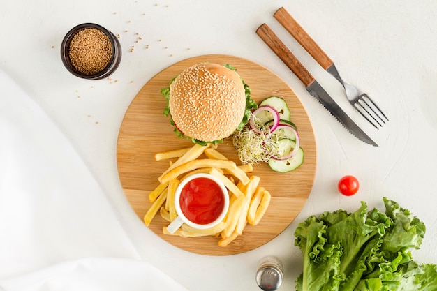 Tablero de madera plano con hamburguesas y papas fritas