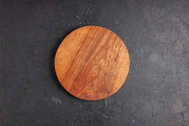 Foto gratuita tablero de madera redonda vista superior sobre fondo oscuro