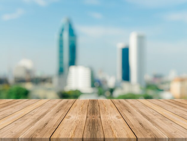 Tablero de madera vacío superior de la mesa de fondo borrosa. Perspectiva mesa de madera marrón sobre fondo borroso ciudad de vista de la construcción - se puede utilizar simulacro para la presentación de productos de montaje o diseño visual de la disposición visual.