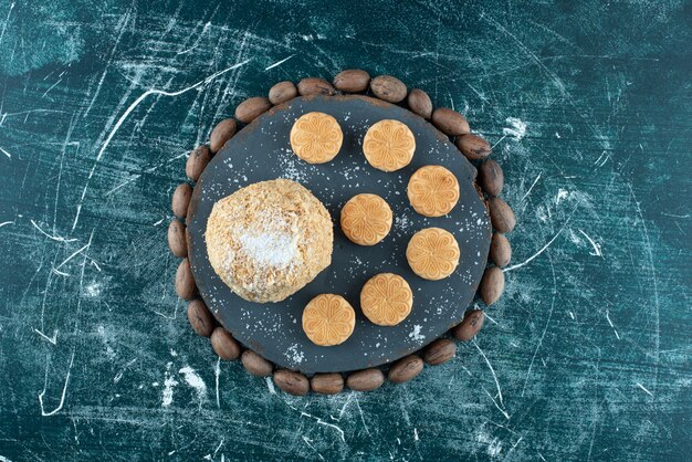 Un tablero oscuro con pastel y galletas sobre un fondo de colores. Foto de alta calidad