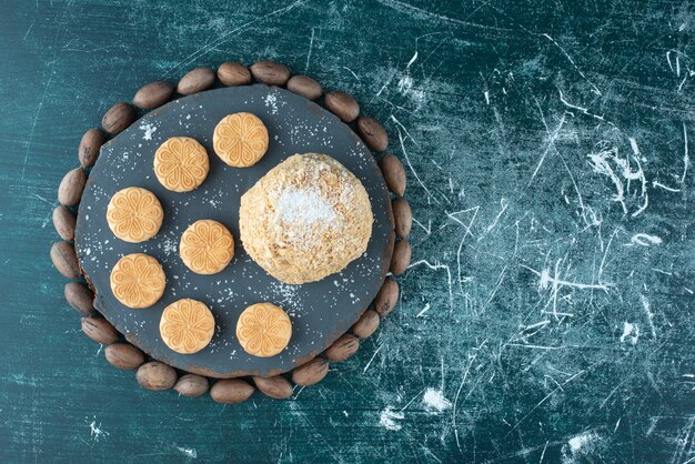 Un tablero oscuro con pastel y galletas sobre un fondo de colores. Foto de alta calidad