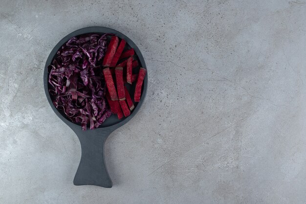 Un tablero oscuro con rodajas de repollo y remolacha. Foto de alta calidad