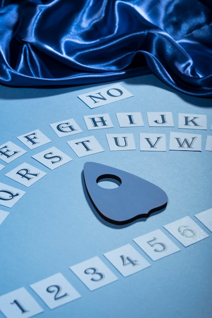 Foto gratuita tablero de ouija y ángulo alto de tela de seda azul.