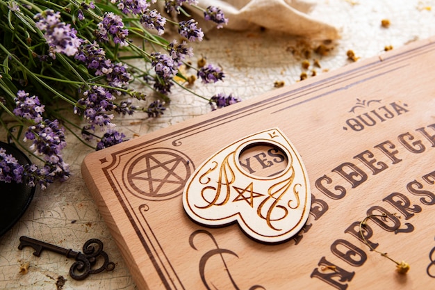 Foto gratuita tablero de ouija y arreglo de flores de alto ángulo.