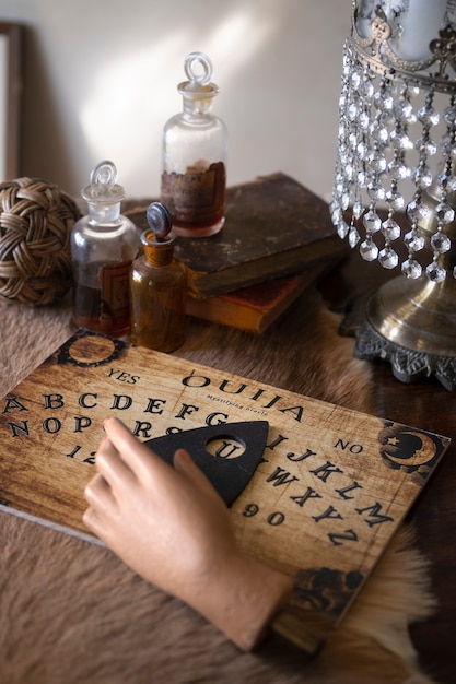 Tablero de ouija y mano falsa en ángulo alto de mesa