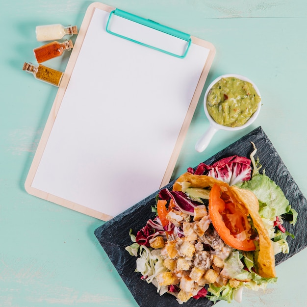 Tablero con plato y guacamole cerca del portapapeles