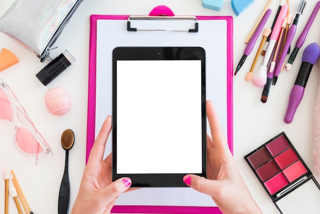 Foto gratuita tablet rodeada de maquillaje