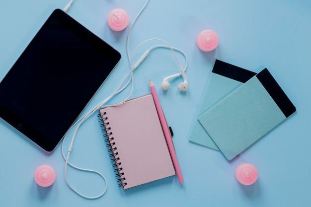 Tableta con auriculares cerca de cuadernos y velas