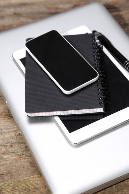 Tableta, computadora, teléfono inteligente, bloc de notas y bolígrafo sobre la mesa