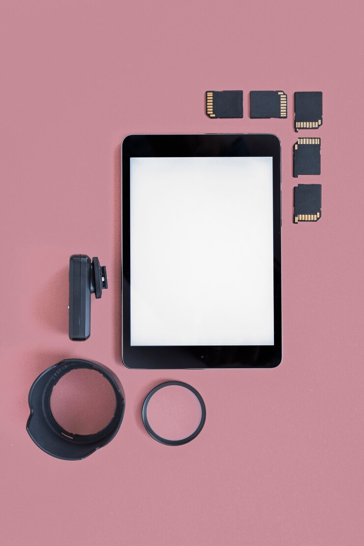 Foto gratuito tableta digital en blanco con tarjetas de memoria y accesorios de cámara sobre fondo coloreado