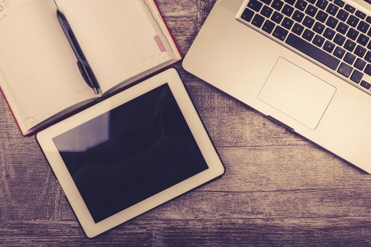 Foto gratuito tableta digital, computadora portátil y un cuaderno para escribir desde arriba sobre un fondo de madera