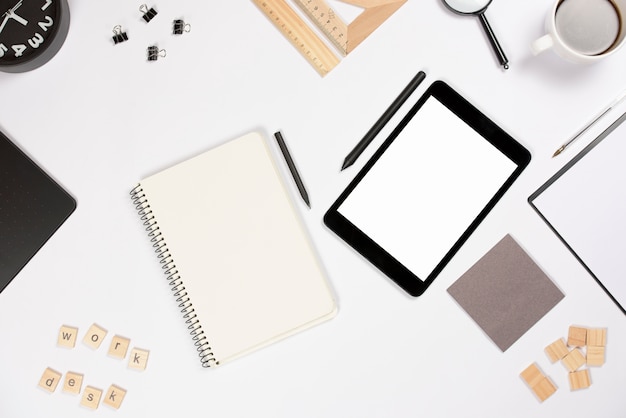 Tableta digital con lápiz y material de oficina sobre fondo blanco