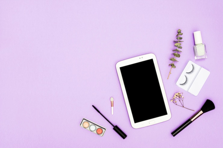 Foto gratuito tableta digital con paleta de sombras de ojos; brocha de maquillaje; botella de esmalte de uñas; cepillo de rímel y botella de esmalte de uñas sobre fondo púrpura