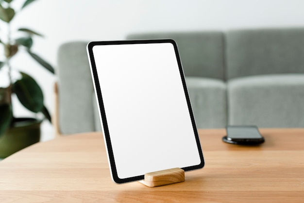 Tableta digital con pantalla en blanco sobre mesa de madera