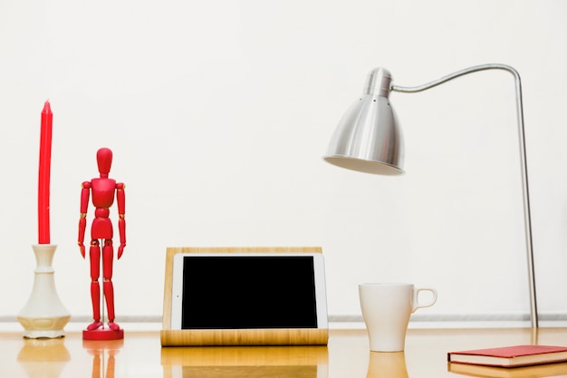 Tableta con maniquí de madera y cuaderno en mesa