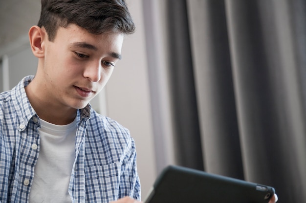 Foto gratuita tableta de navegación del adolescente en la sala de estar