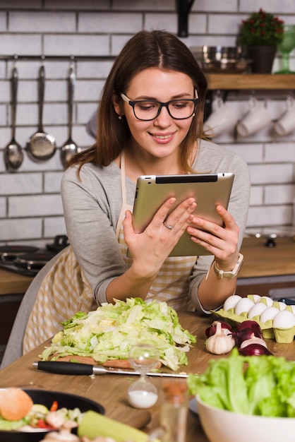 Tableta de observación de ama de casa mientras está de pie en la cocina