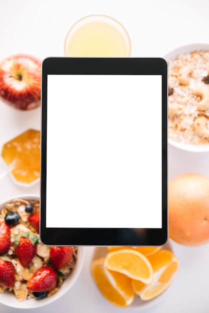 Foto gratuita tableta con pantalla en blanco encima de avena y frutas