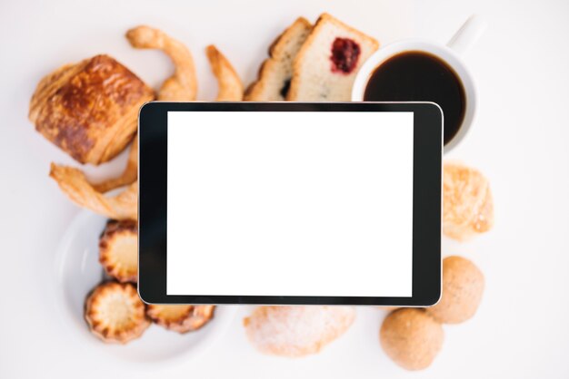 Tableta con pantalla en blanco encima de café con panadería