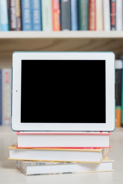 Tableta de primer plano y libros en la biblioteca