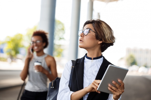 Tableta que se sostiene acertada joven de la empresaria sobre centro de negocios.